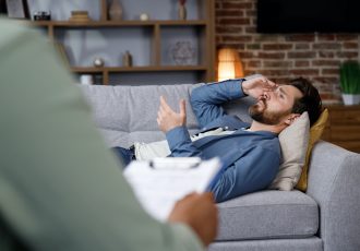 Visit to a psychologist. A handsome man is lying on the couch and talking to a psychotherapist. The